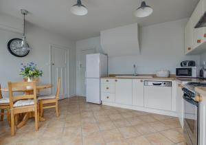 a kitchen with white cabinets and a table and a dining room at Millers Cottage in Woodbridge