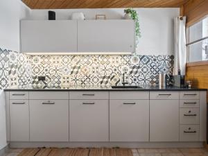 una cocina con armarios blancos y una pared de azulejos en Apartment Schweizerhof 501 Mü by Interhome, en Lenzerheide