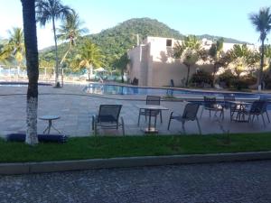 un grupo de mesas y sillas junto a una piscina en Loft Porto Marina Itacuruçá, en Mangaratiba
