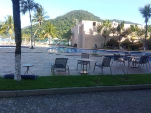 a group of tables and chairs next to a pool at Loft Porto Marina Itacuruçá in Mangaratiba