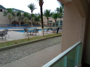 un balcón con mesas y sillas junto a una piscina en Loft Porto Marina Itacuruçá en Mangaratiba