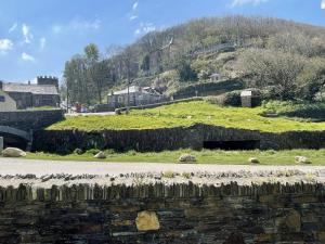 a stone wall next to a road with a hill at The Brewhouse Boscastle Harbour in Boscastle