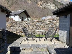 einen Tisch und Stühle auf einer Terrasse mit einer Steinmauer in der Unterkunft Apartment Casa della Posta-2 by Interhome in Rossa