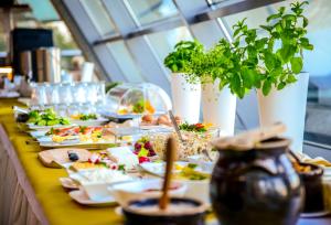 una mesa larga con platos de alimentos y plantas en Hotel Belweder en Ustroń