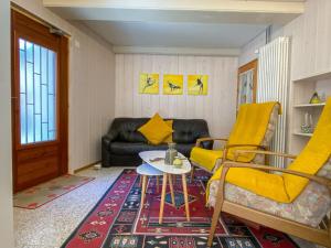 un soggiorno con divano, tavolo e sedie gialle di Apartment Casa della Posta-1 by Interhome a Rossa
