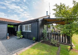 Ein Haus mit einem schwarzen Haus mit einer Terrasse in der Unterkunft Oak Barn Annexe in Trimley Heath