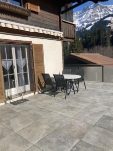 a patio with a table and chairs and a mountain at Apartment Wildbach by Interhome in Adelboden