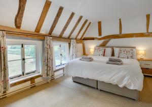 a bedroom with a large white bed and windows at Old Black Horse Farm in Finningham