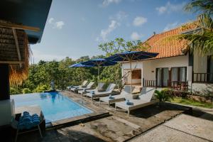 a group of chairs and umbrellas next to a pool at Abasan Hill Hotel and Spa in Nusa Penida