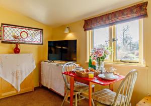 kuchnia z czerwonym stołem z krzesłami i oknem w obiekcie Owls Nest w mieście Stradbroke