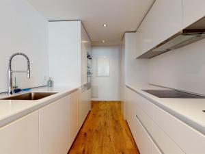 Il comprend une cuisine avec des placards blancs et du parquet. dans l'établissement Apartment Uehlinger Rosana by Interhome, à Lenzerheide
