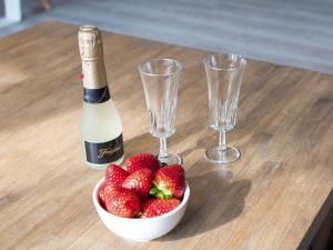 una bottiglia di champagne e una ciotola di fragole su un tavolo di Holiday Home Essen by Interhome a Norddeich