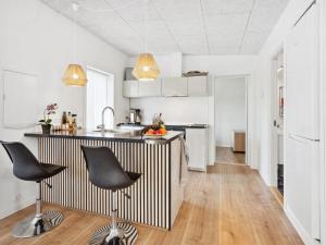 eine Küche mit weißen Schränken und schwarzen Stühlen in der Unterkunft Holiday Home Thorlaf - 200m from the sea in SE Jutland by Interhome in Hejls