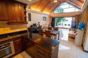 a kitchen with wooden cabinets and a living room at Amazing Beachfront Villa in Ko Lanta