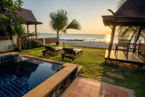 a backyard with a swimming pool next to the ocean at Amazing Beachfront Villa in Ko Lanta