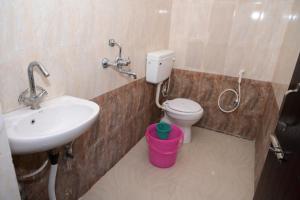 a bathroom with a sink and a toilet with a pink bucket at Dwarka Home Stay in Bodh Gaya