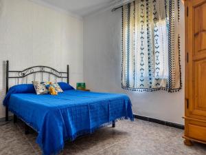 ein Schlafzimmer mit einem blauen Bett und einem Fenster in der Unterkunft Holiday Home San Fernando by Interhome in Villanueva del Río y Minas