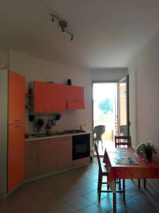a kitchen with orange cabinets and a table and a dining room at Grazioso appartamento terrazzo e wi-fi near Otranto in Casamassella