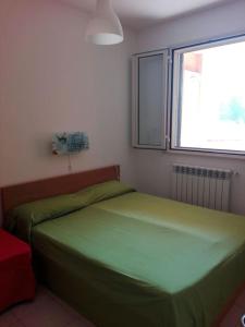 a bedroom with a green bed and a window at Grazioso appartamento terrazzo e wi-fi near Otranto in Casamassella