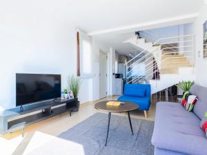 ein Wohnzimmer mit einem blauen Sofa und einem TV in der Unterkunft Apartment Costa Golf Resort by Interhome in Sant Jordi