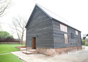 Friston的住宿－Reindeer Cottage Sternfield，一座黑色的建筑,有门和草地庭院