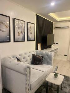 a living room with a white couch and a tv at MAKATI Isabela Luxury in Manila