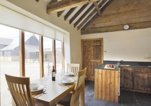 a dining room with a table and chairs and a kitchen at Red House Barns Sternfield in Friston