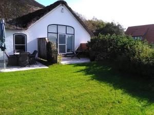 Uma casa branca com um jardim relvado à frente. em Seeperle 3, Wunderschöne Maisonett Ferienwohnung unter Reet! em Sankt Peter-Ording