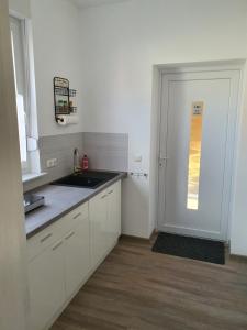 a kitchen with white cabinets and a door with a window at modern und mittendrin, das ist Monty in Wittenberge