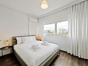 Un dormitorio blanco con una cama con toallas. en Omorfokklisias Apartments by Verde en Atenas