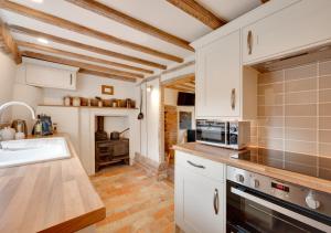a kitchen with white cabinets and a sink and a stove at Perry Acres Cottage in Saxtead