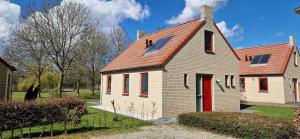 una antigua casa blanca con techo rojo en Lakeview 'Taupo' 4-6 pers by Kawatea Cottages en Ewijk