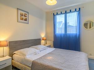 Schlafzimmer mit einem Bett und einem Fenster mit blauen Vorhängen in der Unterkunft Holiday Home Le Large by Interhome in Saint-Philibert