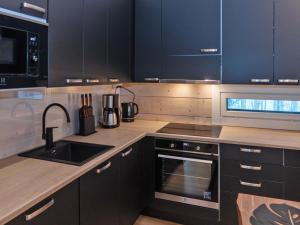 eine Küche mit schwarzen Schränken und einer Spüle in der Unterkunft Holiday Home Mäkitie 2 by Interhome in Aikkila