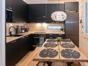 eine Küche mit einem Holztisch und schwarzen Schränken in der Unterkunft Holiday Home Mäkitie 2 by Interhome in Aikkila