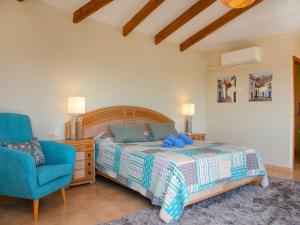 a bedroom with a bed and a blue chair at Holiday Home Mazo by Interhome in Benissa