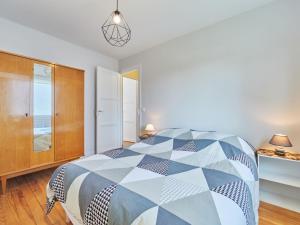 a bedroom with a bed with a blue and white comforter at Holiday Home Janomaine by Interhome in Cabourg
