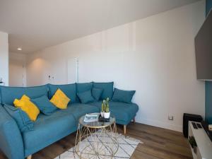 ein blaues Sofa mit gelben Kissen im Wohnzimmer in der Unterkunft Apartment Le Rooftop by Interhome in Lacanau-Océan