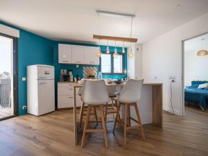 eine Küche mit blauen Wänden sowie einem Tisch und Stühlen in der Unterkunft Apartment Le Rooftop by Interhome in Lacanau-Océan