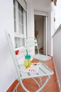una mecedora blanca sentada en un porche en Apartamento El Sol Naciente, en La Herradura
