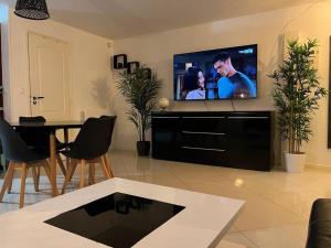 een woonkamer met een tv en een tafel met stoelen bij Super appart 50m² avec jardin V2 in Villeneuve d'Ascq