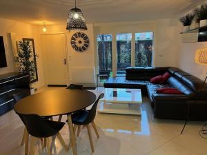 ein Wohnzimmer mit einem Tisch und einem Sofa in der Unterkunft Super appart 50m² avec jardin V2 in Villeneuve d'Ascq
