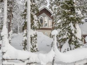 una casa cubierta de nieve frente a los árboles en Holiday Home Levin taiga 18 a by Interhome, en Sirkka