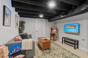 a living room with a couch and a flat screen tv at Modern & Comfy ~ 5* Location~GameRoom~Backyard in Philadelphia