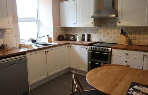 a kitchen with white cabinets and a wooden table at School House in Dunan