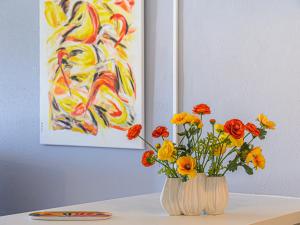 un jarrón de flores sentado en una mesa con un cuadro en Apartment Le Galion by Interhome, en La Trinité-sur-Mer