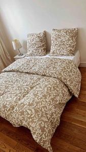 een bed met een bruin en wit dekbed en kussens bij Appartement calme à Bry-sur-Marne in Bry-sur-Marne