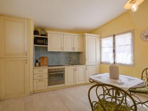 een keuken met witte kasten en een tafel met stoelen bij Apartment La Bastide de Claude by Interhome in La Roquette-sur-Siagne