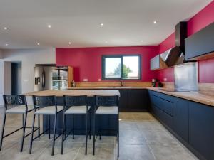 eine Küche mit roten Wänden und eine Bar mit Hockern in der Unterkunft Villa Villa des écureuils by Interhome in Lanton