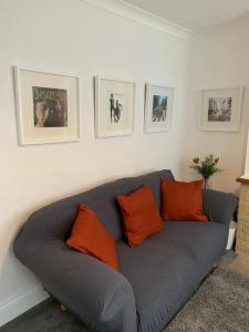 a gray couch with orange pillows in a living room at Church View in Quorndon